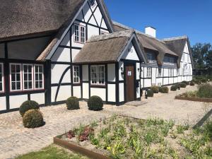 a black and white building with a thatched roof at Hotel Nørrevang in Marielyst