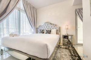 a white bedroom with a large bed and a large window at Calm 3BR Townhouse at Damac Hills 2 Dubailand by Deluxe Holiday Homes in Dubai