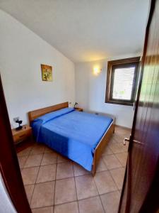 una camera con un letto blu e una finestra di Casa Vacanza Porto Corallo a Villaputzu
