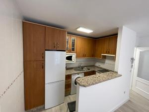 eine Küche mit Holzschränken und einem weißen Kühlschrank in der Unterkunft Escondite Real - Royal Hideaway - Vivienda con Fines Turísticos Hospital de San Miguel in Jaén