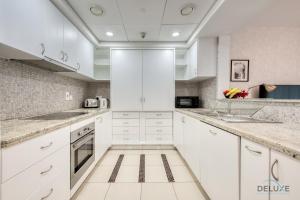 a kitchen with white cabinets and marble counter tops at Airy 1BR at Park Island Sanibel Dubai Marina by Deluxe Holiday Homes in Dubai