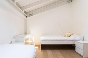 2 łóżka w sypialni z białymi ścianami i drewnianą podłogą w obiekcie White Navigli w Mediolanie