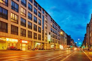 una via cittadina di notte con un edificio di H+ Hotel Berlin Mitte a Berlino