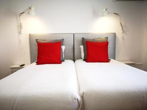 a hotel room with two beds and two lamps at The Bulldog Inn - Duna Parque Group in Vila Nova de Milfontes