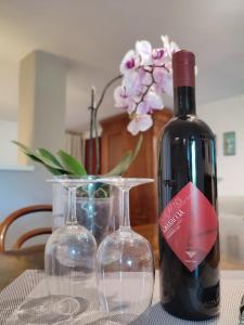 eine Flasche Wein und zwei Weingläser auf dem Tisch in der Unterkunft Independent apartment with a fabulous patio - Casa Penny in Cisano sul Neva