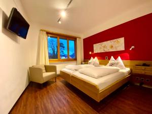 two beds in a room with a red wall at Hotel Toscana in Interlaken
