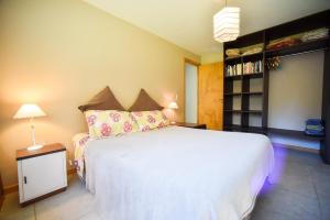 a bedroom with a large white bed and a book shelf at Casa Barrio Acantilados proxima al mar in Mar del Plata