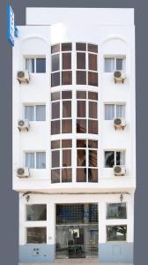a tall white building with windows and a door at hotel azayla in Asilah