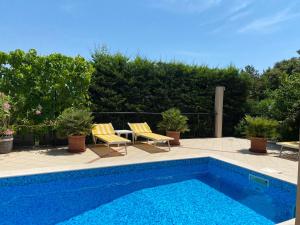a swimming pool with two chairs and a table next to it at Apartments Villa Viktoria in Tivat