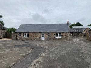 an old stone house with a parking lot in front of it at The Bothy at Arndean in Dollar