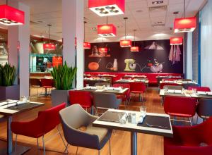 a restaurant with tables and chairs and red chairs at ibis Warszawa West Station in Warsaw