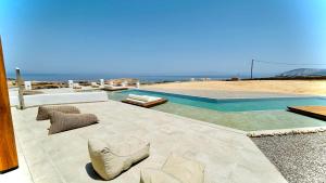 a patio with chairs and a swimming pool next to the beach at Aeris suites Pori in Koufonisia