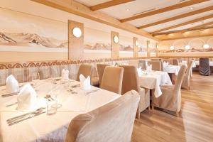 uma sala de jantar com mesas e cadeiras brancas em Hotel Sunny Sölden em Sölden