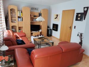 ein Wohnzimmer mit einem roten Ledersofa und einem Tisch in der Unterkunft Ferienwohnungen Am Bruttiger Moselsteig in Bruttig-Fankel