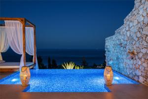a pool at a resort with a bed and a mirror at Emerald Villas & Suites - The Finest Hotels Of The World in Agios Nikolaos