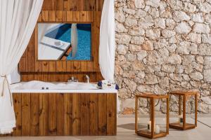 a bathroom with a sink and a mirror and two stools at Emerald Villas & Suites - The Finest Hotels Of The World in Agios Nikolaos