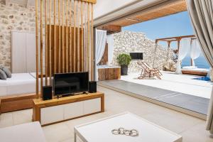 a living room with a tv and a balcony at Emerald Villas & Suites - The Finest Hotels Of The World in Agios Nikolaos