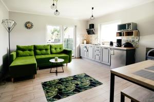 a living room with a green couch and a kitchen at Brzozowy Zakątek in Dąbki