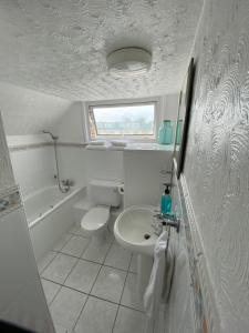 a white bathroom with a sink and a toilet at The Sandhaven in Swanage