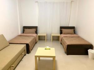 Zimmer mit 2 Betten, einem Sofa und einem Tisch in der Unterkunft شقة الواحة روز - Alwaha Rose in King Abdullah Economic City