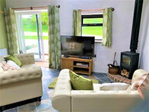 a living room with two couches and a television at Byre Cottages & Log Cabin in Cardigan