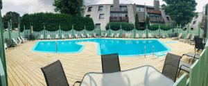 a swimming pool with chairs and a building in the background at Chalet Mont Sainte-Anne in Beaupré