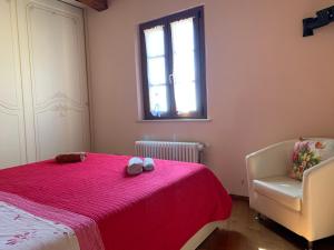a bedroom with a bed and a chair and a window at La Casa degli Archi in Montepulciano