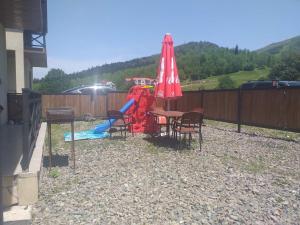 a table and chairs with an umbrella and a playground at Villa Baghdo Bakuriani in Bakuriani
