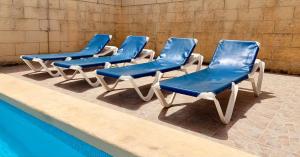 4 sillas azules sentadas junto a una piscina en Hofra Farmhouse, en Victoria