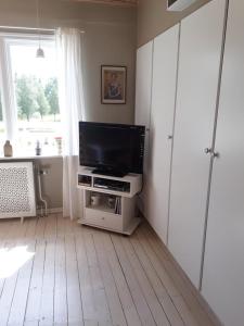 a living room with a flat screen tv on a stand at B&B Parksäter in Håcksvik
