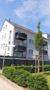 Biały budynek z drzewem przed nim w obiekcie Merve Comfort Aparts4-Hannover w Hanowerze