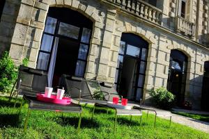 Deux tables dans l'herbe devant un bâtiment dans l'établissement Château Clément - Teritoria, à Vals-les-Bains
