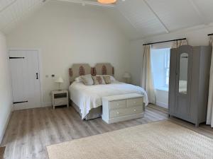 a white bedroom with a bed and a window at The Bothy at Arndean in Dollar +4 photos
