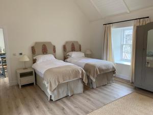 two beds in a white room with a window at The Bothy at Arndean in Dollar