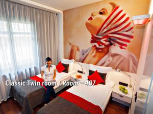 mężczyzna siedzący na łóżku w pokoju hotelowym w obiekcie Bohem Art Hotel w Budapeszcie
