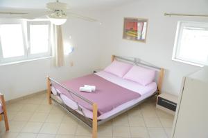 ein kleines Bett in einem Zimmer mit zwei Fenstern in der Unterkunft Apartments Marina in Ražanac