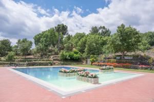 a swimming pool with flowers in a garden at Santoro Country House in Castiglione di Sicilia