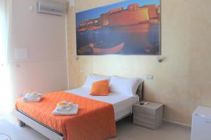 een slaapkamer met een bed met oranje lakens en een schilderij bij Aden B&B Salento in Sannicola