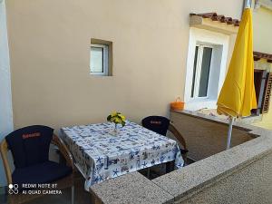 a table and chairs with a table and a umbrella at Apartman in Cres