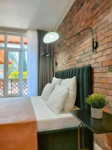 a bedroom with a bed and a brick wall at Амра Санрайз in Tsandrypsh