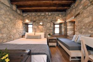 1 dormitorio con 2 camas y un banco en una pared de piedra en Casa La Bohema, en Afitos