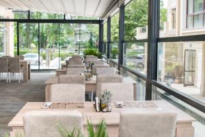 a row of tables and chairs in a restaurant with windows at Cinema Hotel in Primorsko