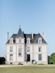 uma grande casa branca com um telhado preto em Les Garennes - Hôtel Spa Bénodet em Bénodet