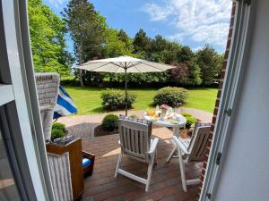 a patio with a table and chairs and an umbrella at NTAB10002-FeWo-Moeoevwarder-twee in Neue Tiefe Fehmarn