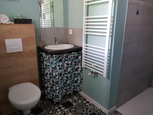 La salle de bains est pourvue de toilettes blanches et d'un lavabo. dans l'établissement Chambres d'hôtes couleur bassin d'Arcachon, à Andernos-les-Bains