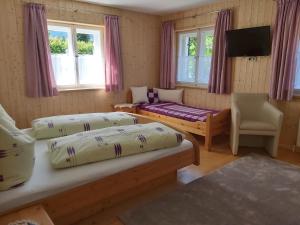 a room with two beds and a chair and windows at Haus Klinger in Gaschurn