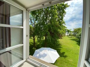 una ventana abierta con una sombrilla blanca en el césped en NTAB10104-FeWo-Moeoevwarder-veer, en Neue Tiefe Fehmarn