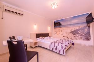 a bedroom with a bed and a painting of a beach at Vila Lorena in Mamaia Sat/Năvodari