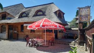 a table with an umbrella in front of a building at Casa Buga in Vişeu de Sus