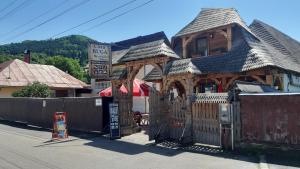 a wooden house with a gate and a fence at Casa Buga in Vişeu de Sus